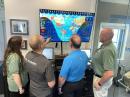 Geochron Owner Patrick Bolan (second from left) demonstrates the digital Geochron to ARRL staff members (left to right) Jherica Goodgame, KI5HTA; Bob Naumann, W5OV, and Steve Goodgame, K5ATA. [Bob Inderbitzen, NQ1R, photo]